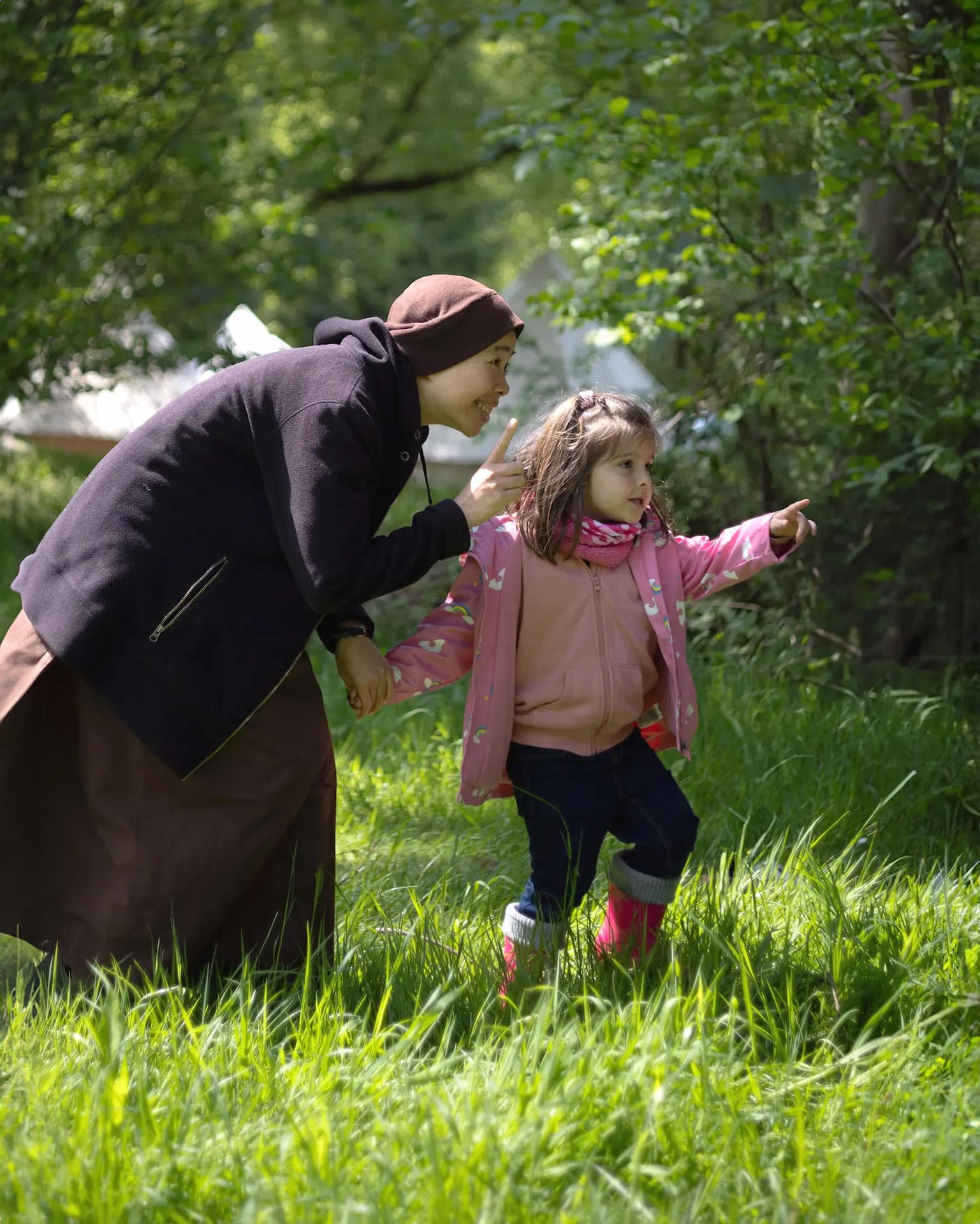 plum village nun joyfully holding the hand of a child and pointing towards a tree during a walking meditation